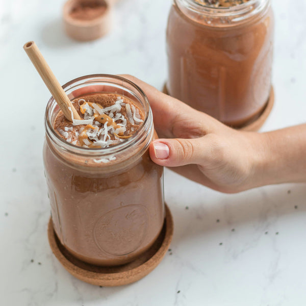 A hand reaching for a chocolate smoothie made with Habthera Nutrition ASP-1™ Adaptive Support Powder